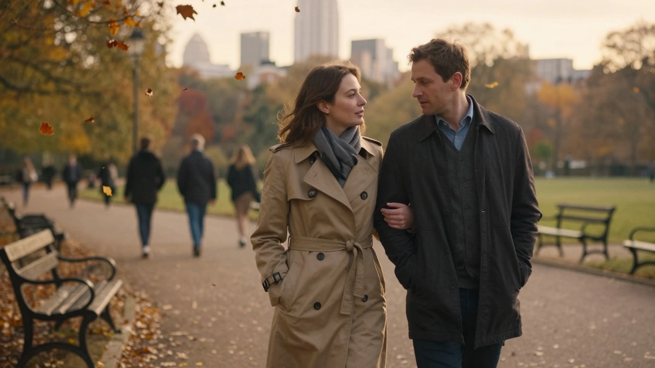 A couple walking side by side through Hyde Park at dusk, autumn leaves falling as they talk with gentle closeness.